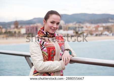 Happy female standing at pier in cold spring day