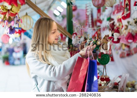 Happy young beautiful woman choosing Christmas decoration at market