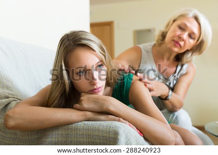 Elderly mother gives solace to unhappy adult daughter at home. Focus on girl