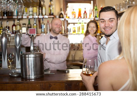 Positive bartender entertaining guests at bar counter