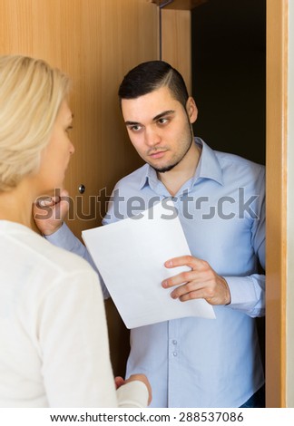 Male agent trying to collect money from aged blonde housewife at home door