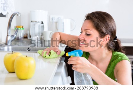 Beautiful woman doing chores around the house thoroughly cleaning furtniture in kitchen