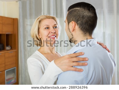 Adult son asking happy mother to dance at home
