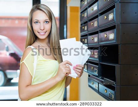 Young smiling woman checking up letter-box indoor