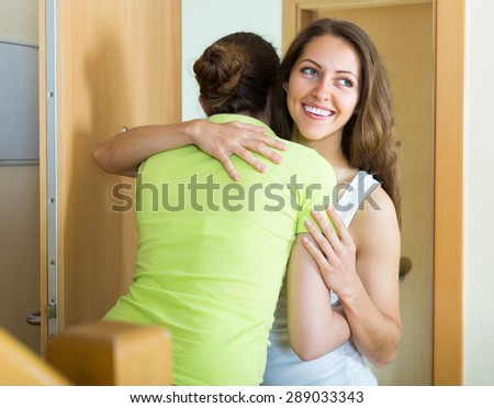 Cheerful smiling girl meeting girlfriend at the door