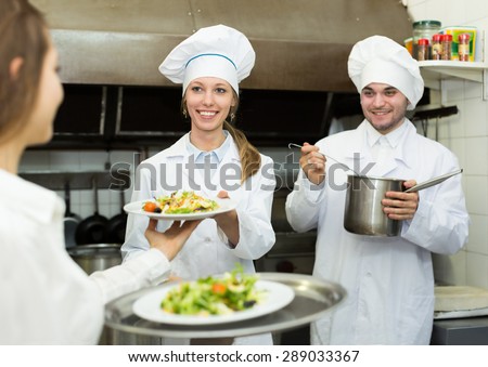 Team of chefs and young waiter in the restaurant kitchen