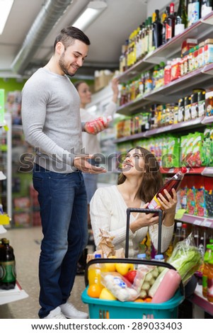 Portrait of happy customers standing at beverages section of the supermarket