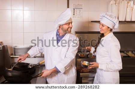 Portrait of smiling chef with beautiful young female helper at restaurantÃ¢??s kitchen