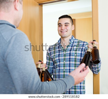 Happy adult man visiting friend and bringing beer