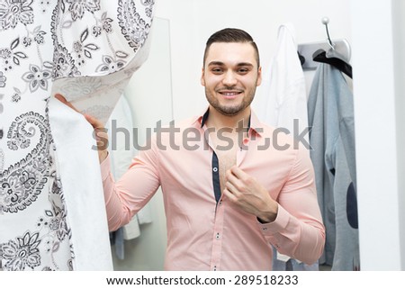 Handsome young man standing at boutique changing cubicle