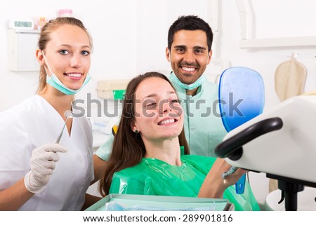 Smiling woman patient checks the result of the work of the dentist