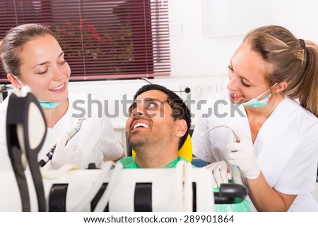 Smiling guy and positive dental clinic crew during teeth check up. Selective focus