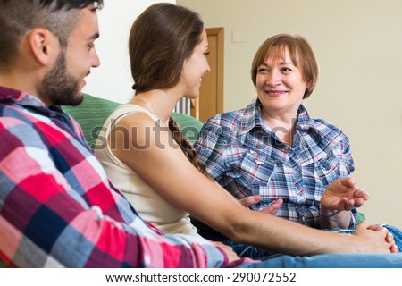 Smiling elderly mother talking to her adult children at home