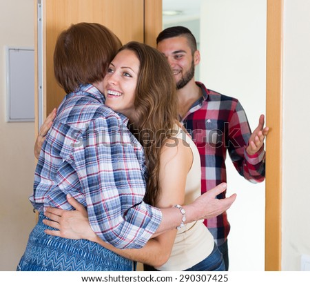 Senior woman meeting  young couple at the door