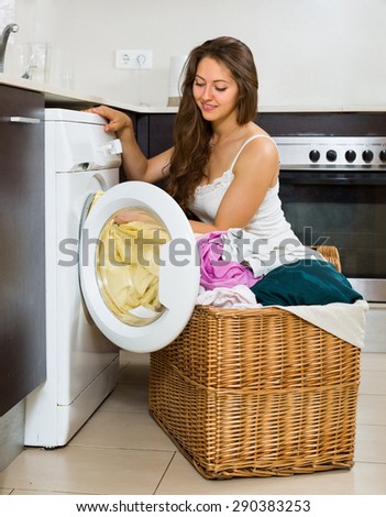 Home laundry. Young woman using washing machine at home kitchen