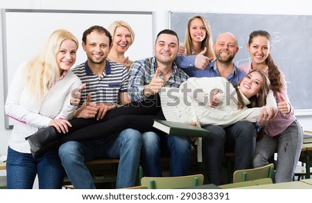 Happy female professor and cheerful students posing in classroom at extension courses