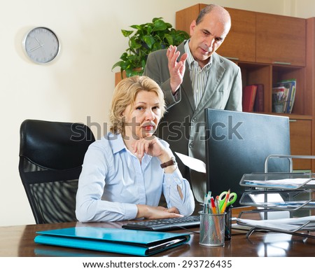 Angry boss screaming at his mature female assistant in office