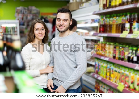 Portrait beautiful couple standing near shelves with canned goods at shop