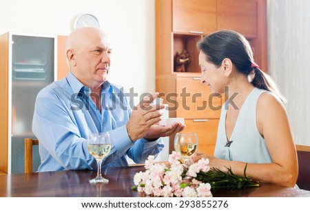 Happy mature man giving  woman the jewel in box  at home