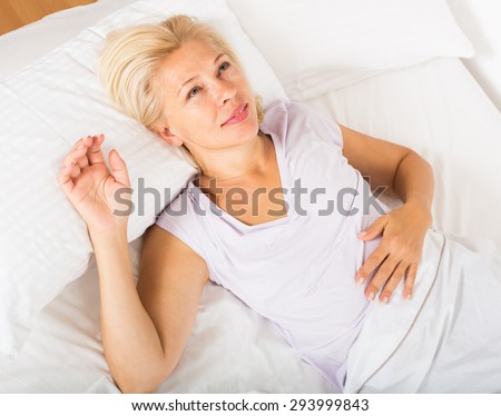 mature lady in shirt awaking on bed at bedroom
