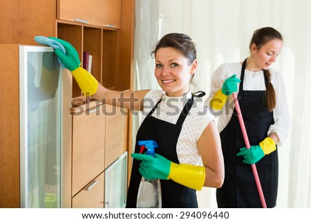Happy professional cleaners washing apartment with rag and mop