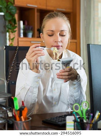 Young hungry woman having fast lunch at office desk