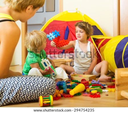 Young mother and children playing with  toys indoor