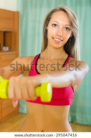 Young woman working out with dumbbells at home