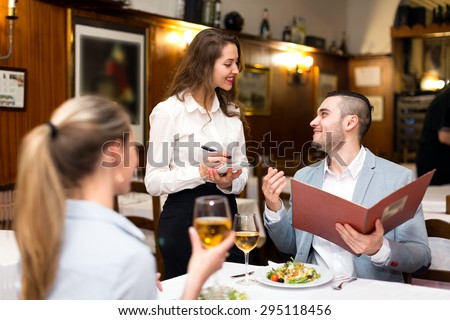 Beautiful couple dining in a restaurant while happy waitress is taking their order