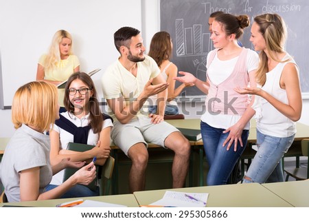 Relaxed students chatting with each other in classroom during a break between studying sessions
