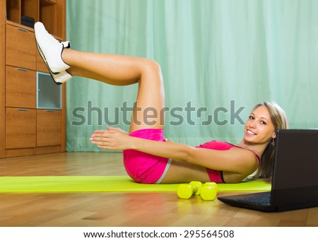 Positive smiling young woman working out with notebook in gym