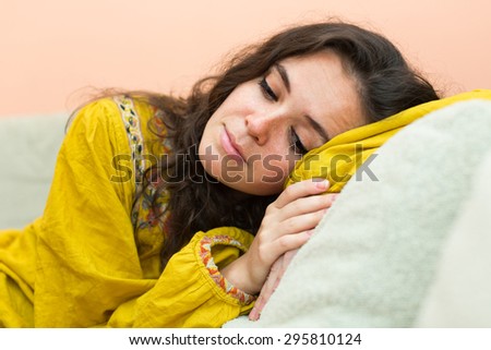 Sad and lonely woman in  yellow dress sitting on couch at home