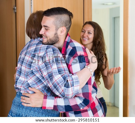 Elderly woman meeting  young couple at the door