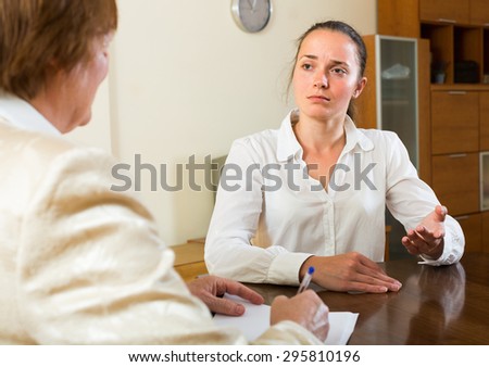 Mature lady and a young woman having a serious meeting at desk in the office