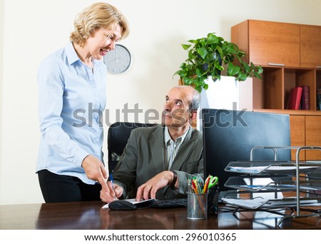 scene of two mature and smiling co-workers in office
