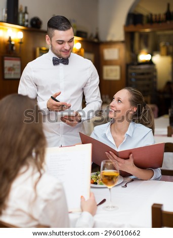 Smiling waiter serving bar guests with beverages