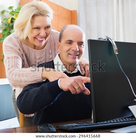 Happy elderly couple talking with someone online and smiling at home