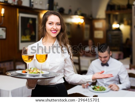 Smiling russian female waiter serving guests table in restaurant