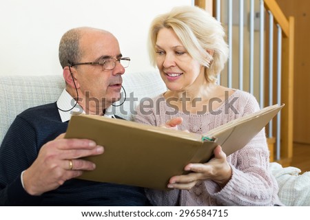 Portrait of senior spouses with picture album indoors