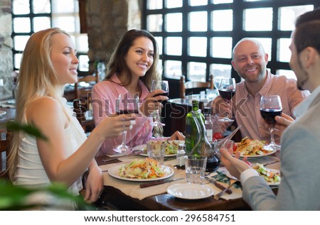 Portrait of smiling young adults having dinner in family restaurant. Focus on brunette girl