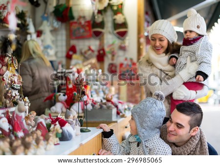 A handsome man with his wife and children shopping at a christmas fair. Shallow focus. Focus on man.