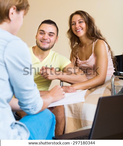 Happy couple with disabled woman talking with female social worker indoor