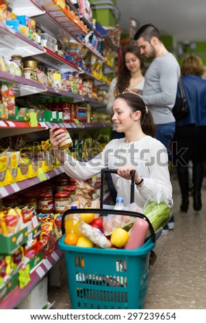 Young happy female purchasing food for week at supermarket