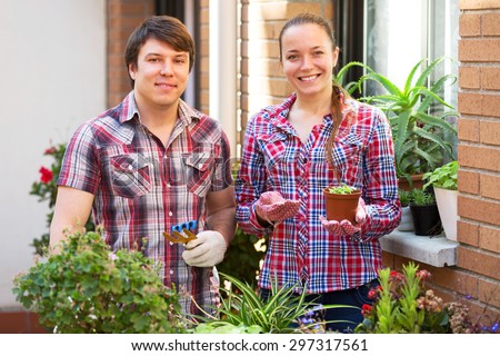 Happy young couple works with flowers in sunny day
