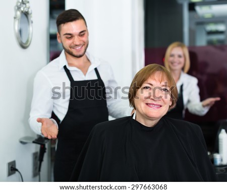 Portrait of smiling elderly woman cutting hair in the barbershop