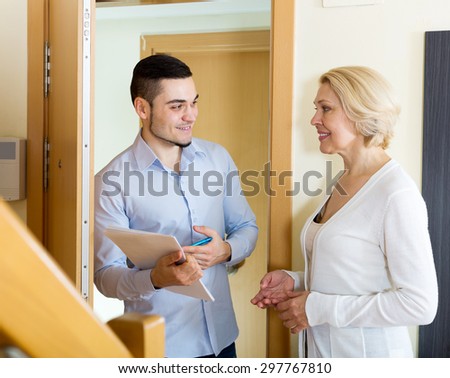 Smiling woman answers the questions of adult employee  in door at home