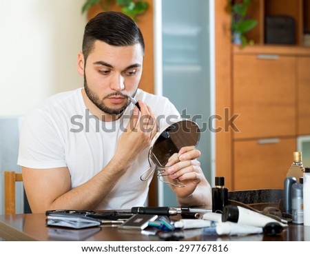 Young man shaves moustache with a trimmer