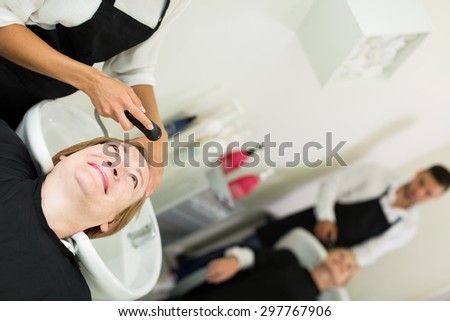 hairdresser wash head to the elderly happy woman in the salon