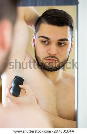Positive guy shaving armpit with electric razor