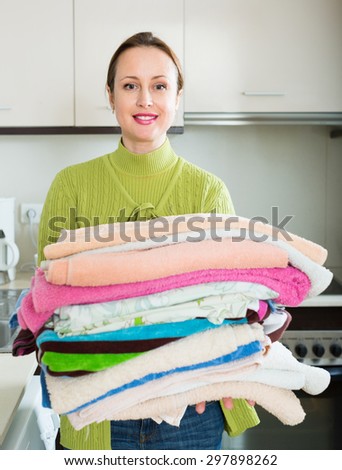 Home laundry. Brunette woman in green loading clothes into washing machine in home